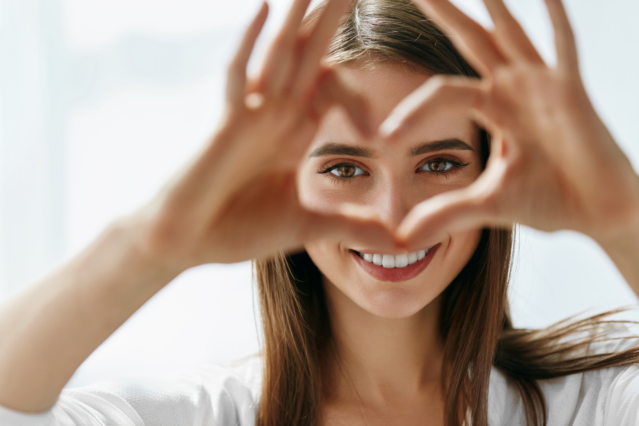 Woman Holding Heart Shaped Hands Near Eyes.